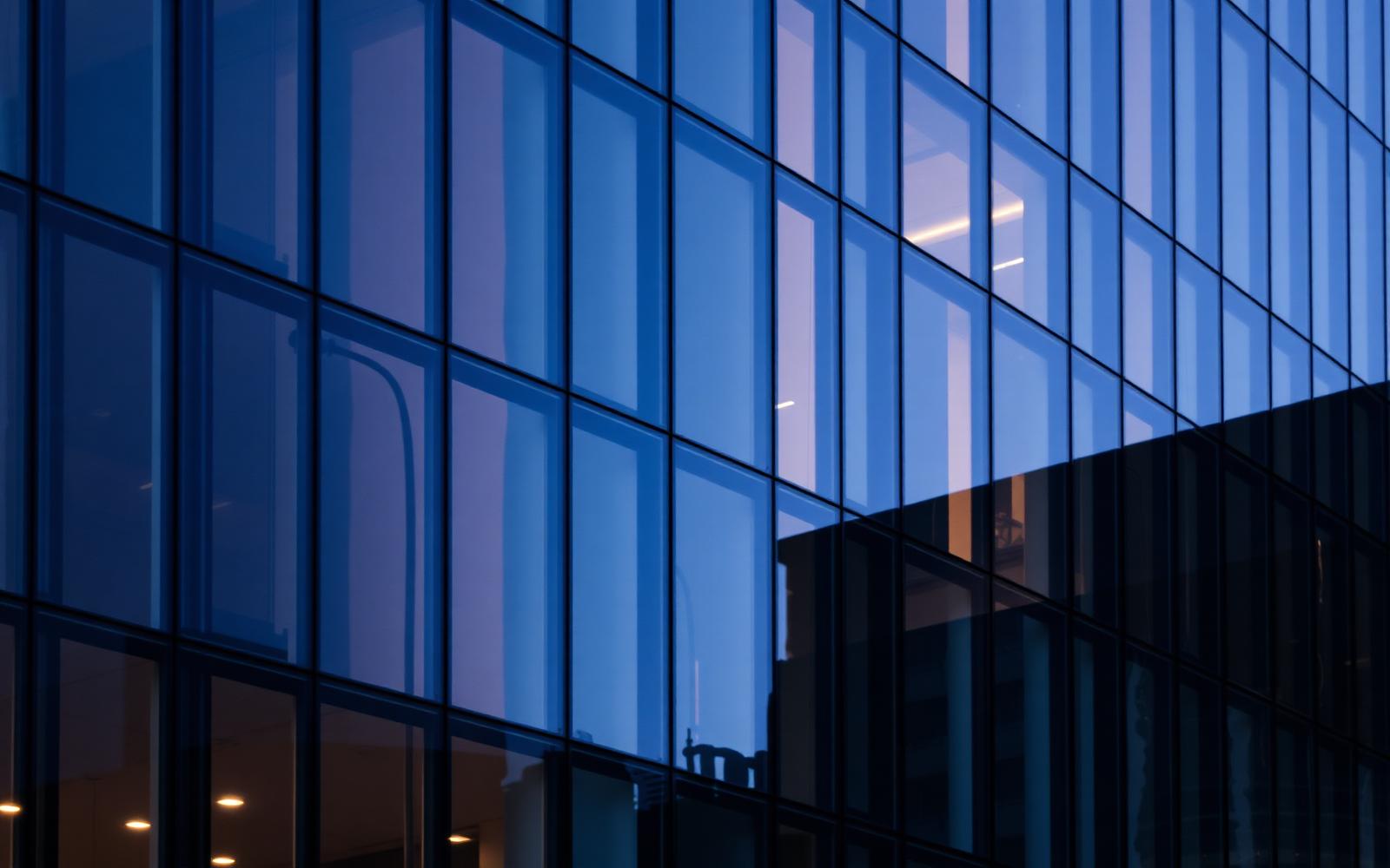 Moderne Glasfassade eines Bürogebäudes in der Abenddämmerung